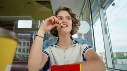 Young Adult Eats French Fries in Restaurant