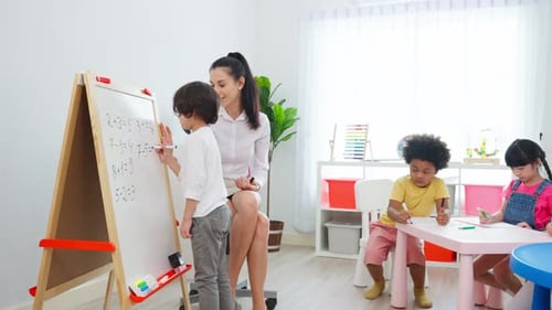 Caucasian beautiful woman teacher teaching a lesson to kid student in classroom at school.
