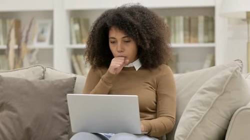 Young Woman Coughing While Working on Laptop