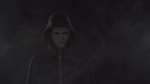 Mysterious Figure in Mask and Hoodie Stands in Smoke