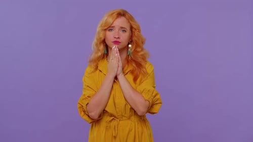 Woman begs with hands together in a dress