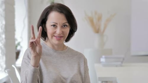 Smiling Woman Giving Peace Sign, Indoors