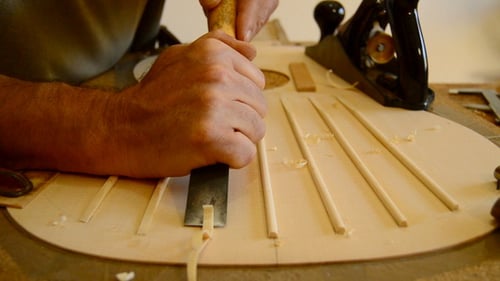Luthier Making a Guitar Structure with a Chisel