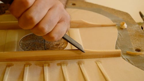 Luthier Shaping Guitar Wood with a Chisel