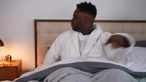 Un jeune homme afro-américain inquiet et anxieux, allongé dans son lit la nuit, fait des efforts pour s'endormir