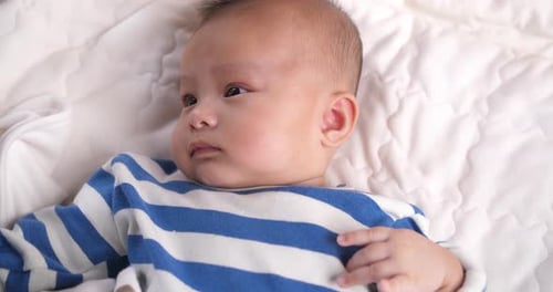 Cute Infant Laying on White Blanket