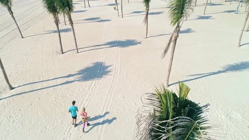 Drone point of young couple running on the beach. Shot with RED helium camera in 8K