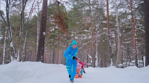 Sporty Man Smiles and Runs Drawing Sled with Family in Park