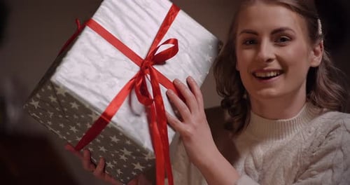 Woman Holding Christmas Present Wrapped with Red Ribbon