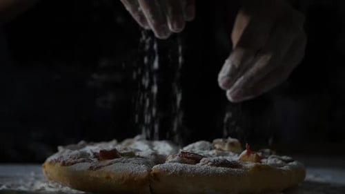 Zeitlupe von Frauenhänden, die Mehl auf Pizza sieben