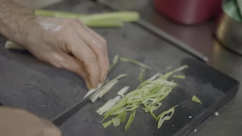 Chef Slicing Green Onions on Cutting Board