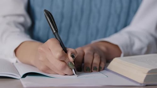Woman Writing in Notebook at School Desk