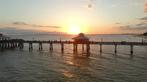 People looking to a beautiful sunset over the ocean in Fort Myers Pier, Florida