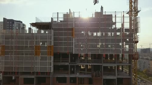 Hisser la caméra le long d'un bâtiment en construction avec des travées vides et des travailleurs sur le