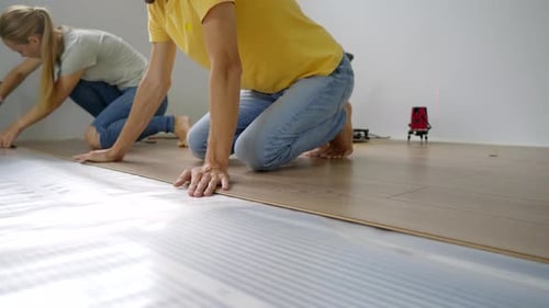 Adults Installing Laminate Flooring in Home