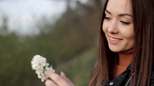 Beautiful Woman Holds Flowering Branch and Smiles
