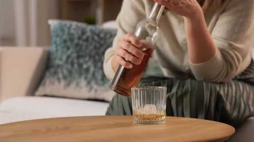 Woman Pours Liquor into Glass at Home