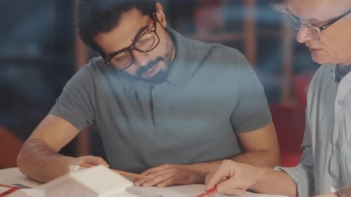 Architects Reviewing Building Plans Together at Night
