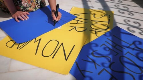 Mädchen, das auf blauem Plakat schreibt, steht mit der Ukraine für die Unterstützung der Ukraine gegen den Krieg.