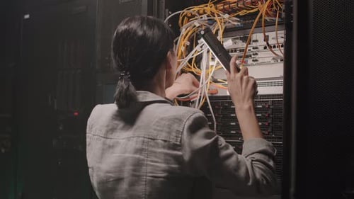 Woman Adjusting Server Cables in Data Center