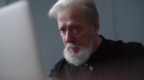 Senior Man Uses Laptop Computer at Home