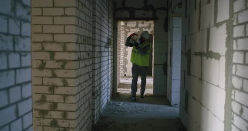 Builder Carrying Pipes Inside Unfinished Building