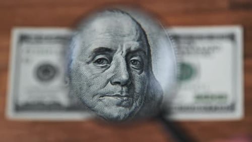 Magnifying Glass Scrutinizing a Hundred Dollar Bill