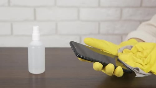 Disinfecting Phone Screen with Gloves and Spray