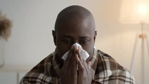 Man Holding Tissue to Nose Indoors