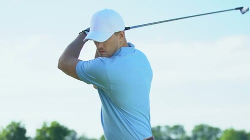 Male Golfer Swings Club on Green Golf Course