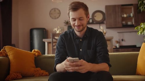 Man Relaxing on Couch with Smartphone
