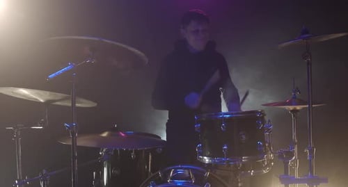 Young Adult Plays Drums in Smoky Night Club