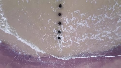 Beautiful aerial view of an old wooden pier at the Baltic sea coastline, overcast day, white sand be