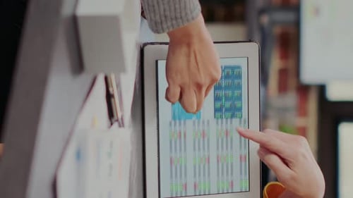 Collaborateurs vidéo verticaux examinant les statistiques boursières sur tablette