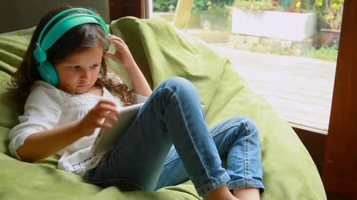 Girl Using Tablet with Headphones on Beanbag Chair
