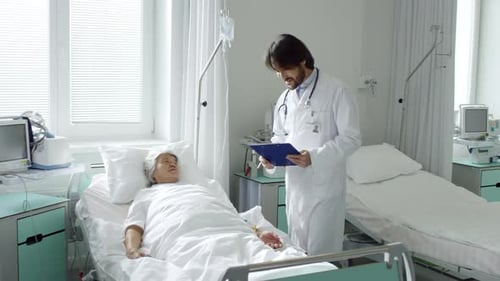 Doctor Talking with Senior Woman in Hospital Bed