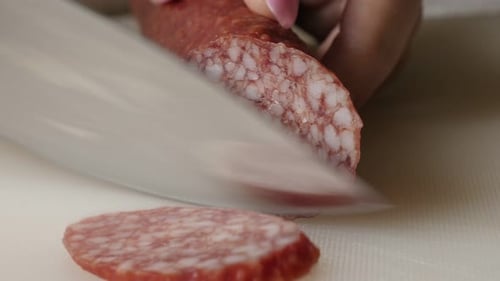 Cutting cured sausage of air-dried meat close-up 4K 2160p 30fps UltraHD footage - Salami cut on smal