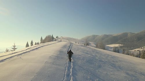 Aerial View of Backpacker Hiking Snowy Mountain Hillside on Cold Winter Morning