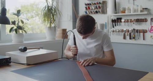Man Working Leather with Tool in Bright Studio