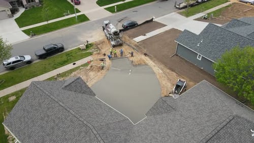 Concrete crew working together to finish long new driveway in residential neighborhood.