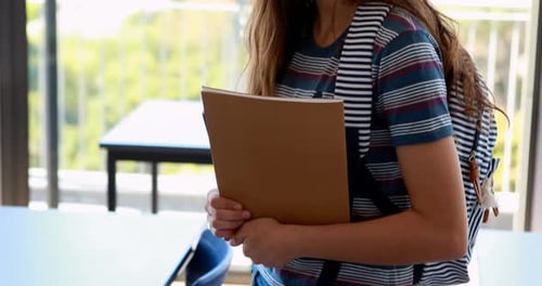 Smiling Teen Student with Books in Classroom