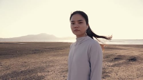 ttractive young Asian woman athletic looking at camera while standing on the beach.