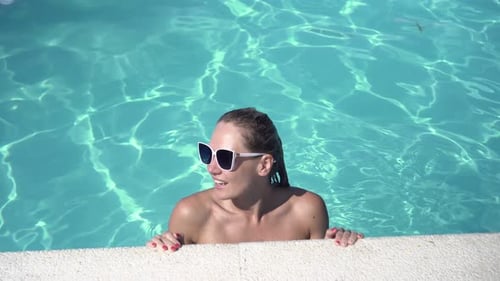 Junge attraktive Frau entspannt sich in einem Sommerschwimmbad mit blauem Wasser