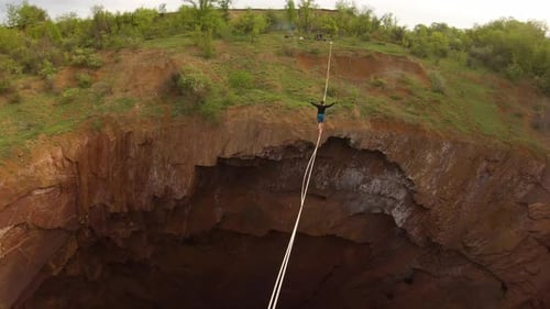 Aerial View on a Man Walking on the Slackline Over a Massive Pit Drone