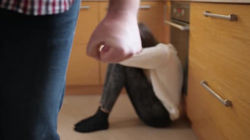 Distraught Woman Sitting on Kitchen Floor, Man Clenched Fist