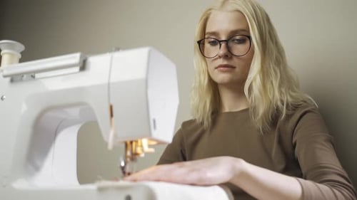 A Young Woman Seamstress Works at a Sewing Machine