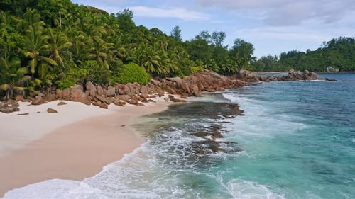 Aerial Low Altitude Fly Over Exotic Tropical Beach with Rocks Palm Trees and Ocean Waves at Mahe