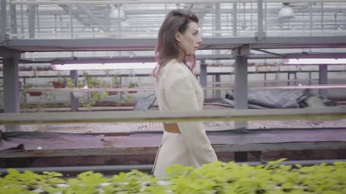 Woman Walking in a Modern Greenhouse Full of Plants