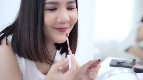 Woman Applying Lip Gloss in Bright Setting
