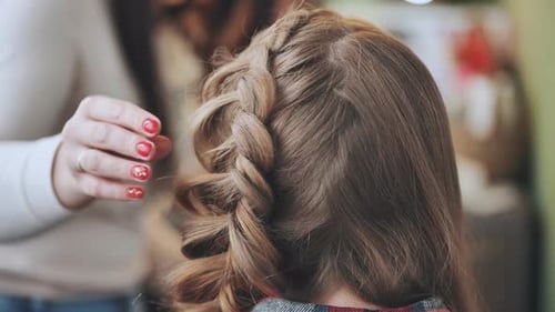 The Girl Makeup Artist Makes a Braid for the Model